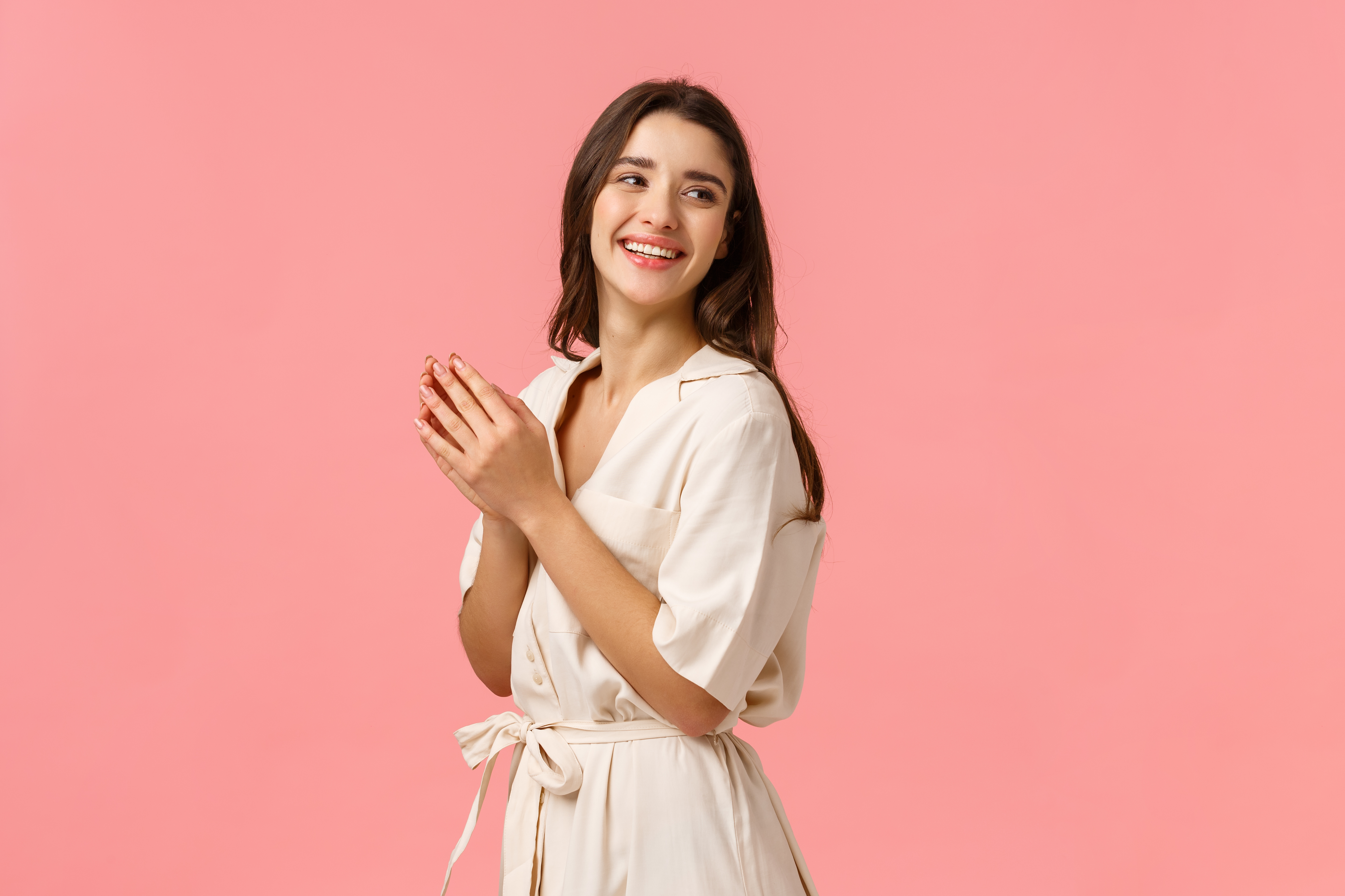 Fashion, leisure and beauty concept. Cheerful elegant and tender female tourist relaxing on spa resort, applying body lotion, hand cream, looking behind right side copy space, pink background