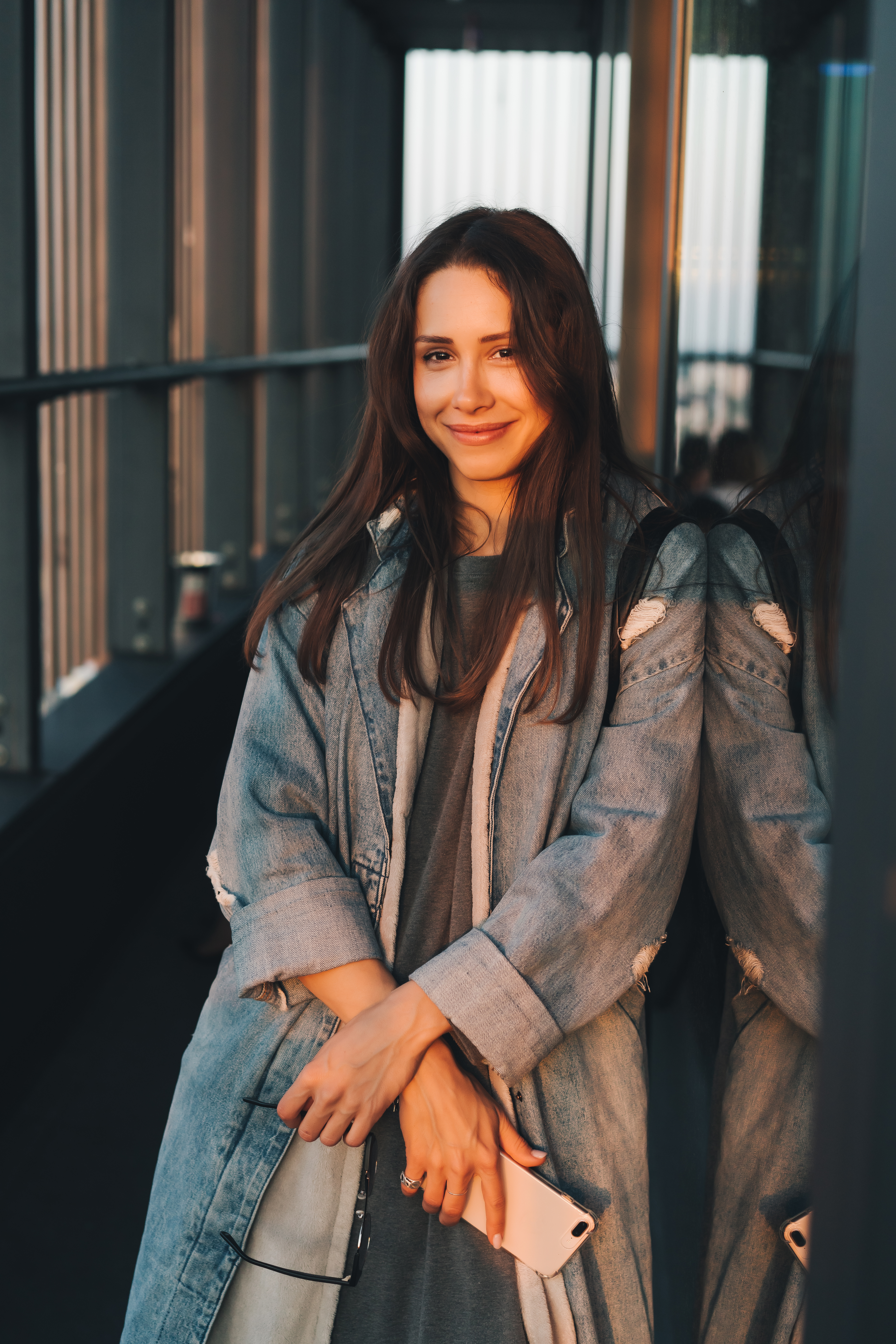 Portrait of a young attractive emotional girl dressed in a trendy blue denim coat